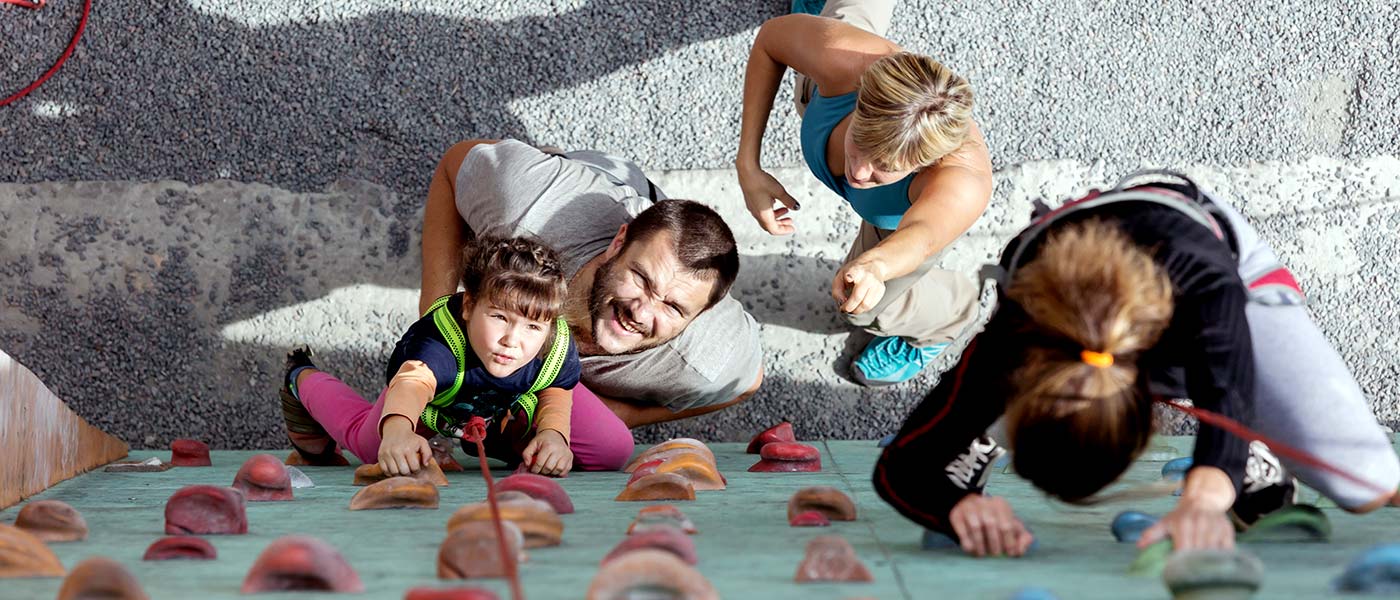 Family receiving instruction how to use a climbing wall